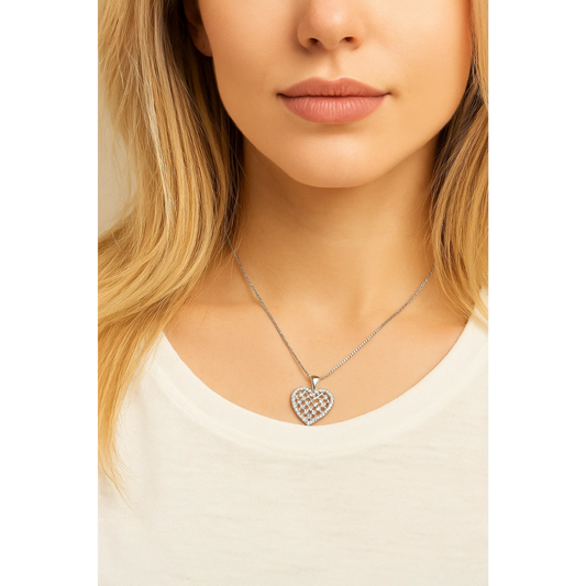 A woman wears the Crystal Heart Necklace, a silver heart pendant with a checkered design and sparkling cubic zirconia, along with a white top. Only the lower half of her face and upper chest are shown.