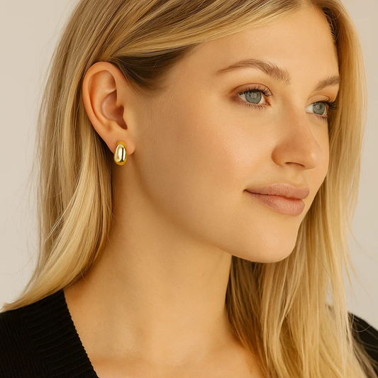 Gold dome huggie hoop earrings on model with black top