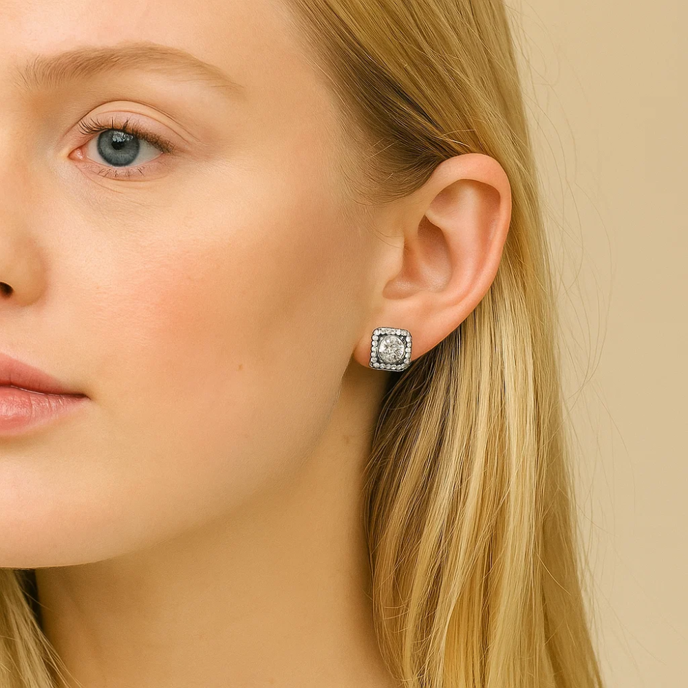 A close-up of a woman with long blonde hair wearing Katlyn Crystal Stud Earrings—square-shaped, white gold plated studs with a sparkling central stone and smaller accents—against a neutral background.