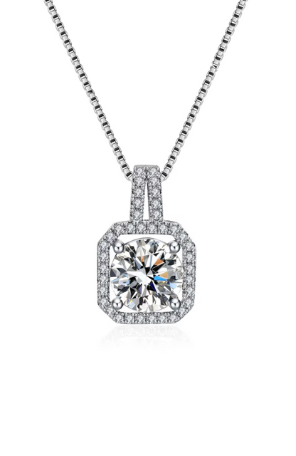 The Two Carat Halo Cubic Zirconia Pendant Necklace features a large, round cz stone surrounded by a square halo of smaller stones, all set in a sleek, silver geometric metal frame.