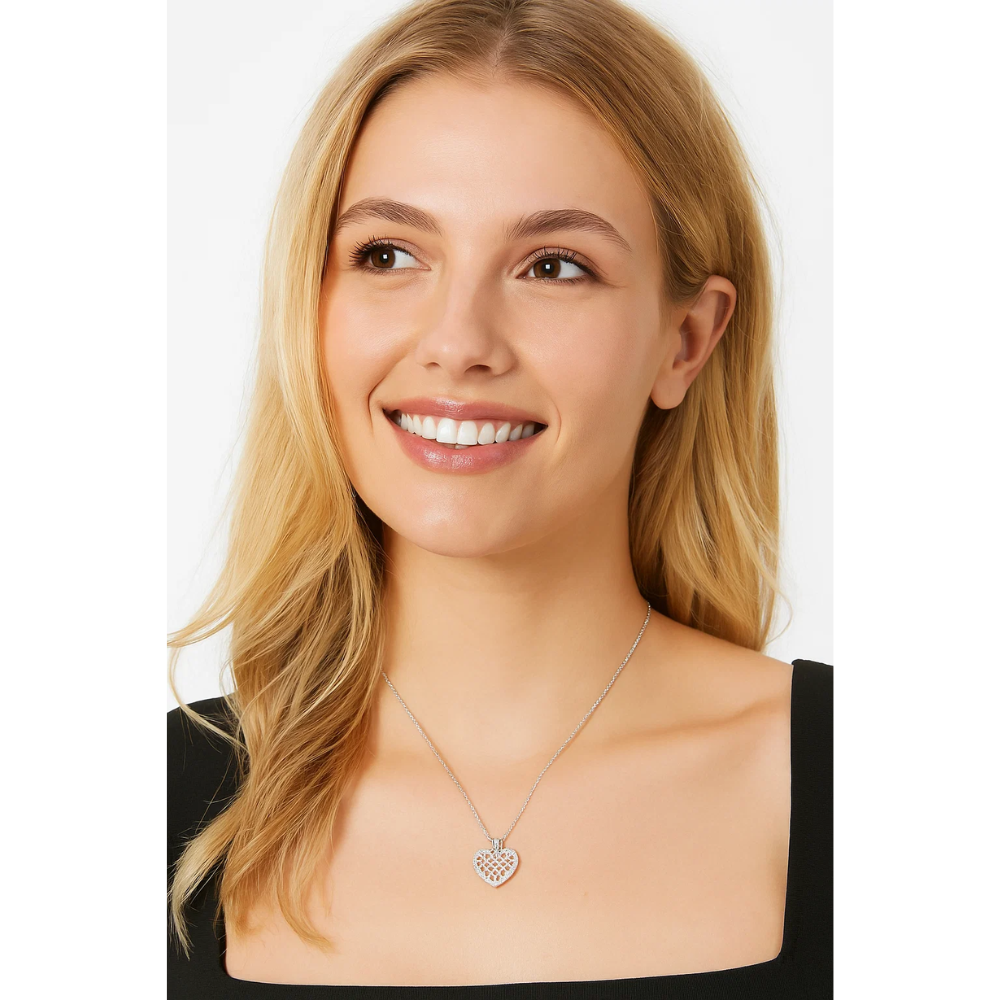 A smiling woman with long blonde hair wears a black square-neck top and the Crystal Heart Necklace, featuring a silver heart encrusted with sparkling cubic zirconia. She is looking slightly to her left.