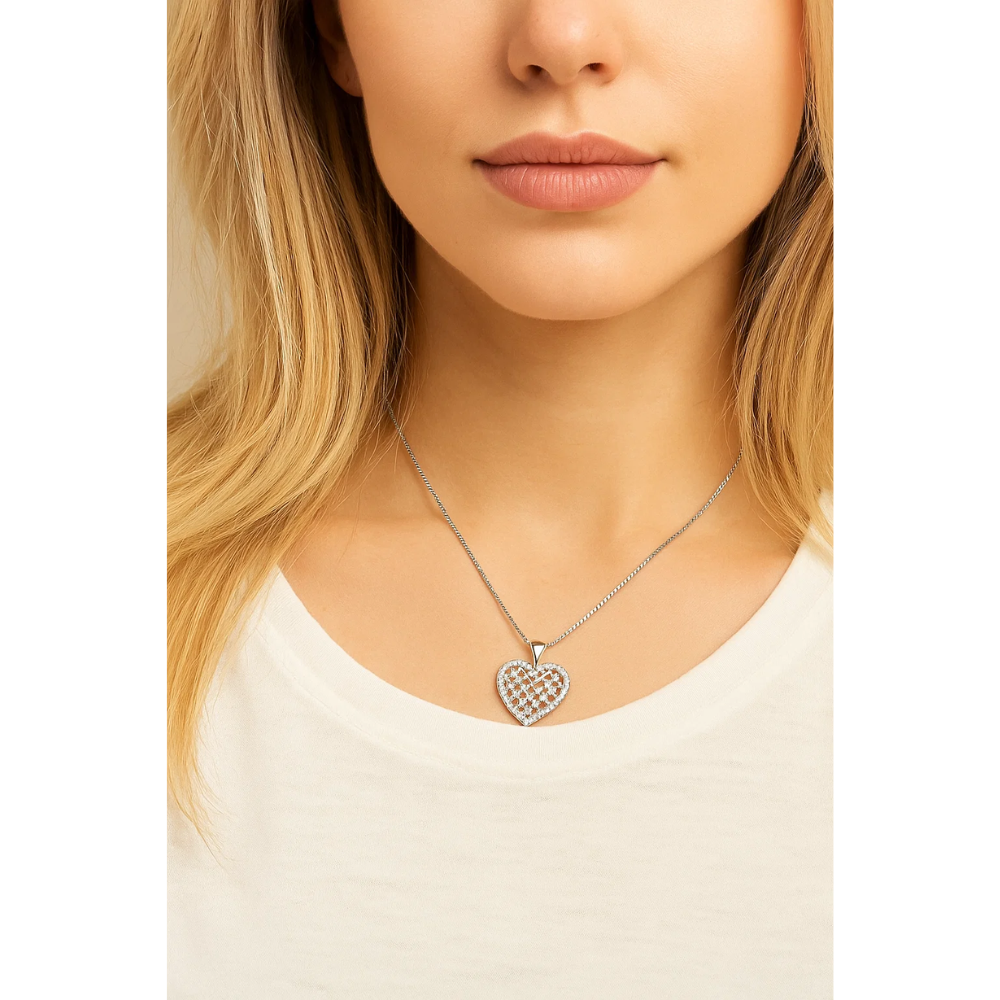 A woman wears the Crystal Heart Necklace, a silver heart pendant with a checkered design and sparkling cubic zirconia, along with a white top. Only the lower half of her face and upper chest are shown.