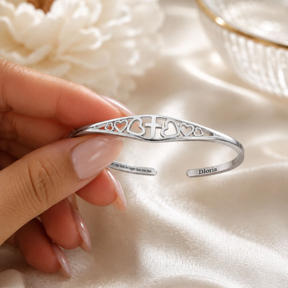 Silver adjustable cuff bracelet close-up with cross-and-heart cutout engraving and quote