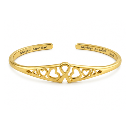 Gold engraved adjustable cuff bracelet with heart cutout ribbon motif on the front