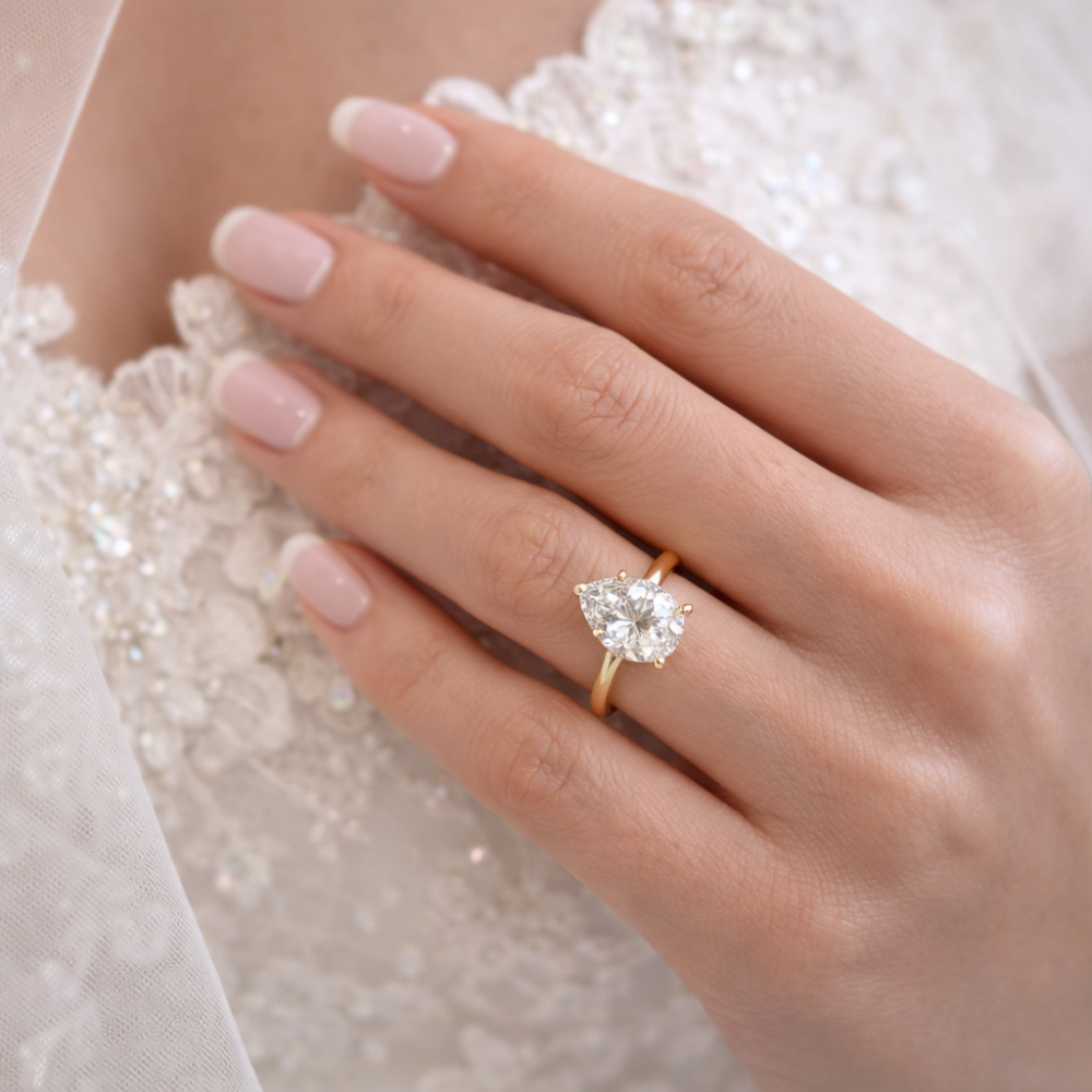 Pear-cut moissanite ring in gold-tone with a small teardrop stone on the finger.
