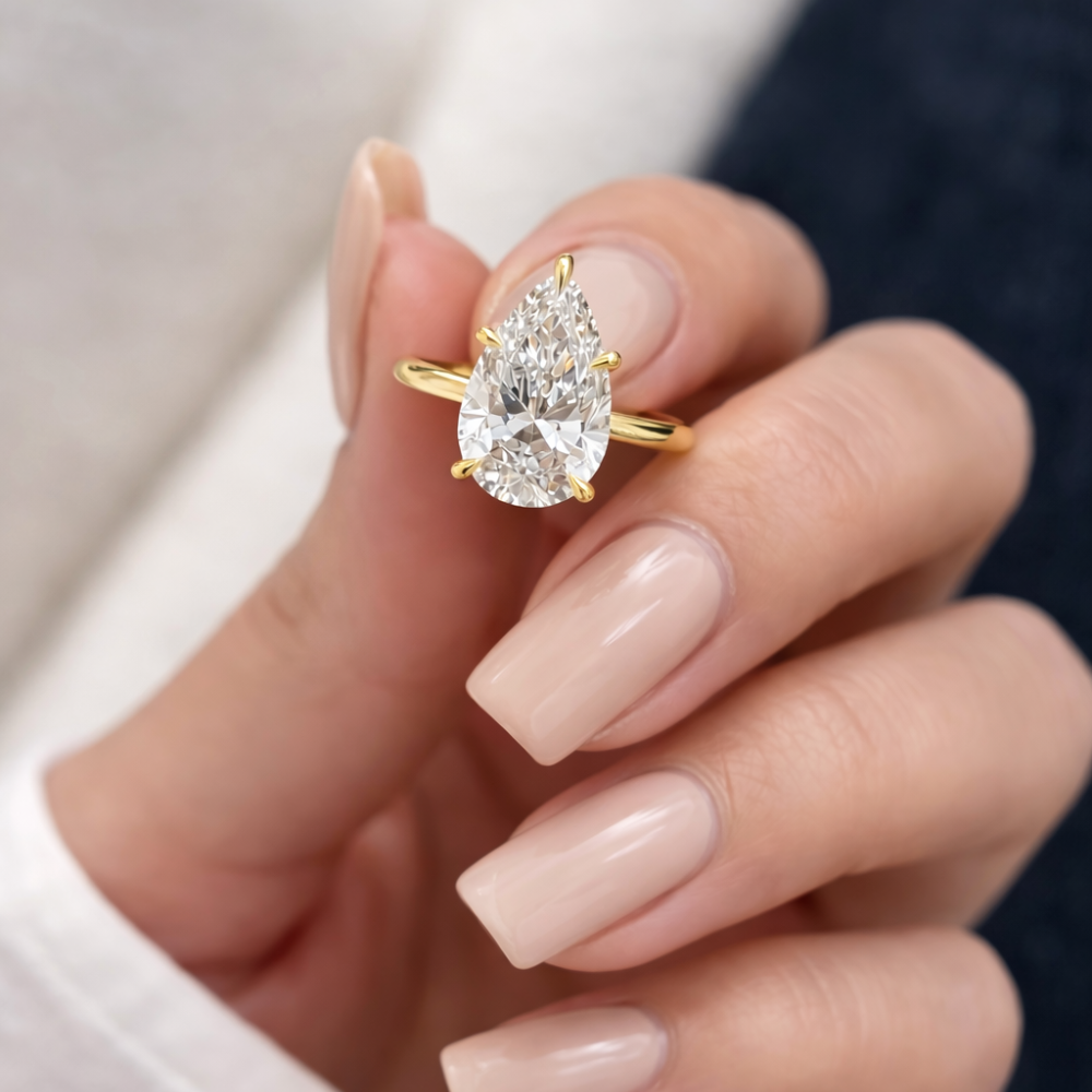 Gold-tone pear-cut moissanite ring featuring a faceted teardrop center stone.