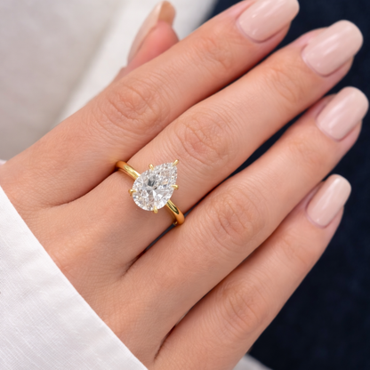 Gold-tone pear-cut moissanite ring with a faceted teardrop stone, slim band.
