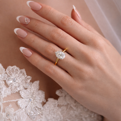 Gold-tone pear-cut moissanite ring with a teardrop stone, slim band on hand.