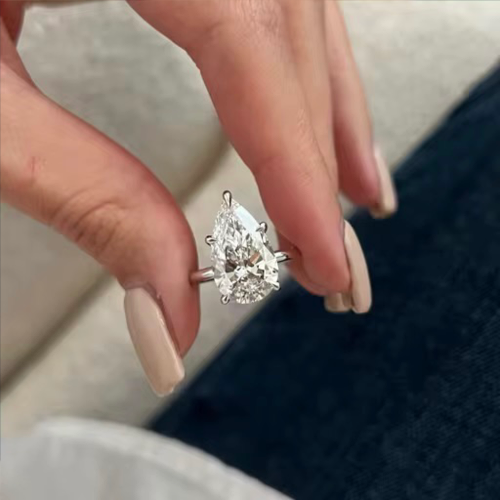 Silver-tone pear-shaped gemstone ring on finger with open prong band