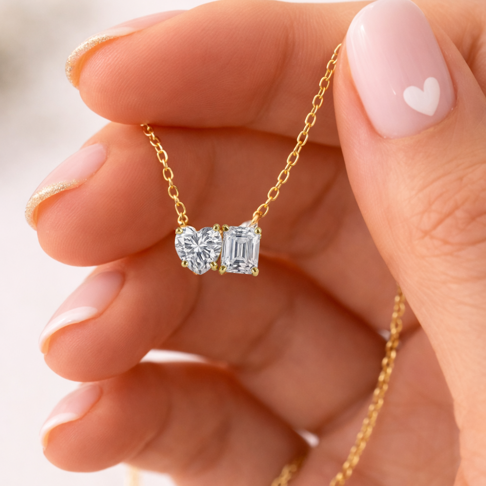 Close-up of gold vermeil necklace with heart and emerald-cut moissanite stones in gold prongs
