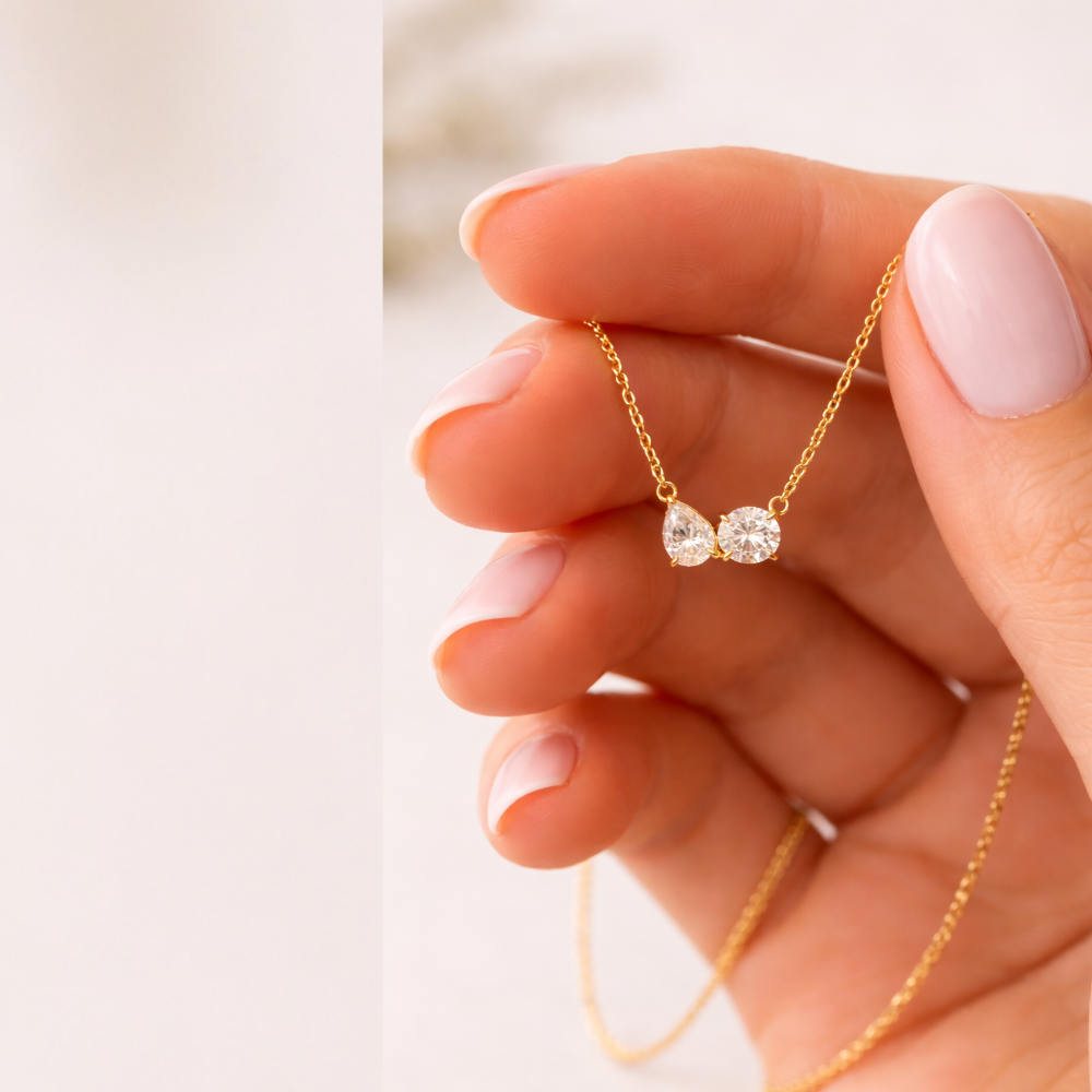 Gold vermeil necklace pendant with pear and round-cut clear stones held in hand