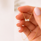 Gold vermeil necklace pendant with pear and round-cut clear stones held in hand