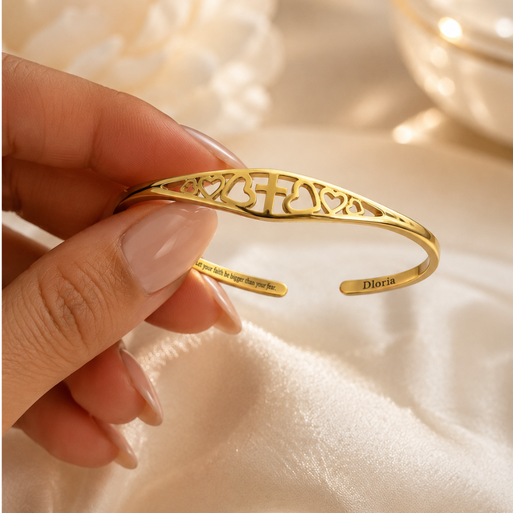 Gold heart-and-cross cuff bracelet close-up with inner quote engraving