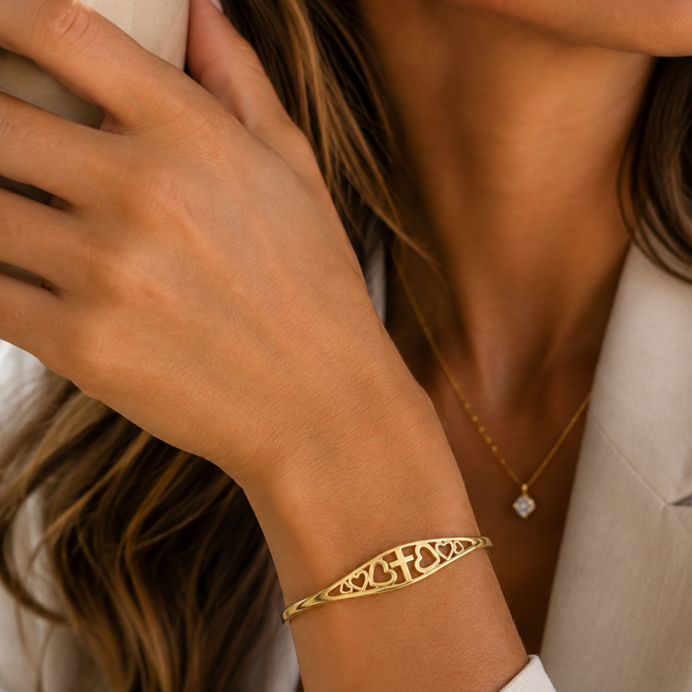 Gold heart-and-cross engraved cuff bracelet on wrist, fine filigree detail