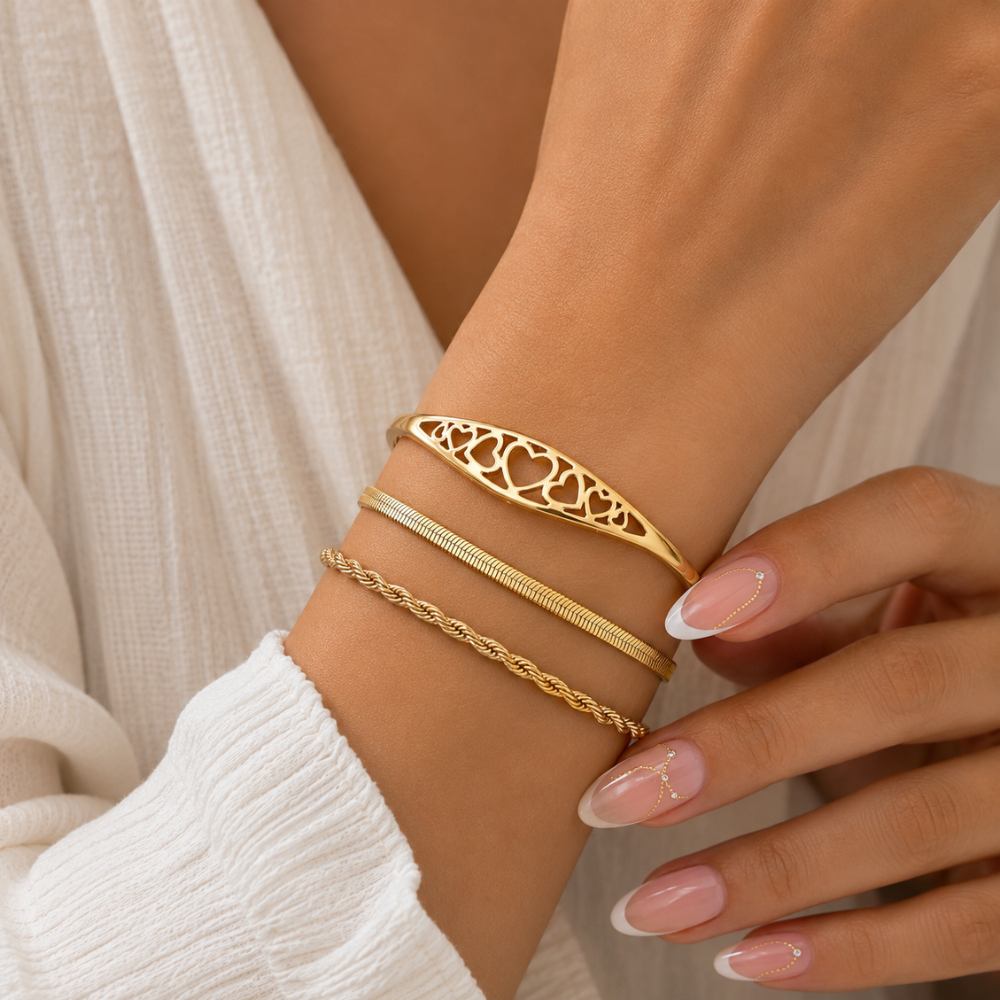 Gold engraved heart cuff bracelet close-up on wrist with heart filigree band