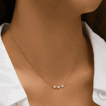 Gold-tone three-stone cubic zirconia necklace on model neckline with thin chain