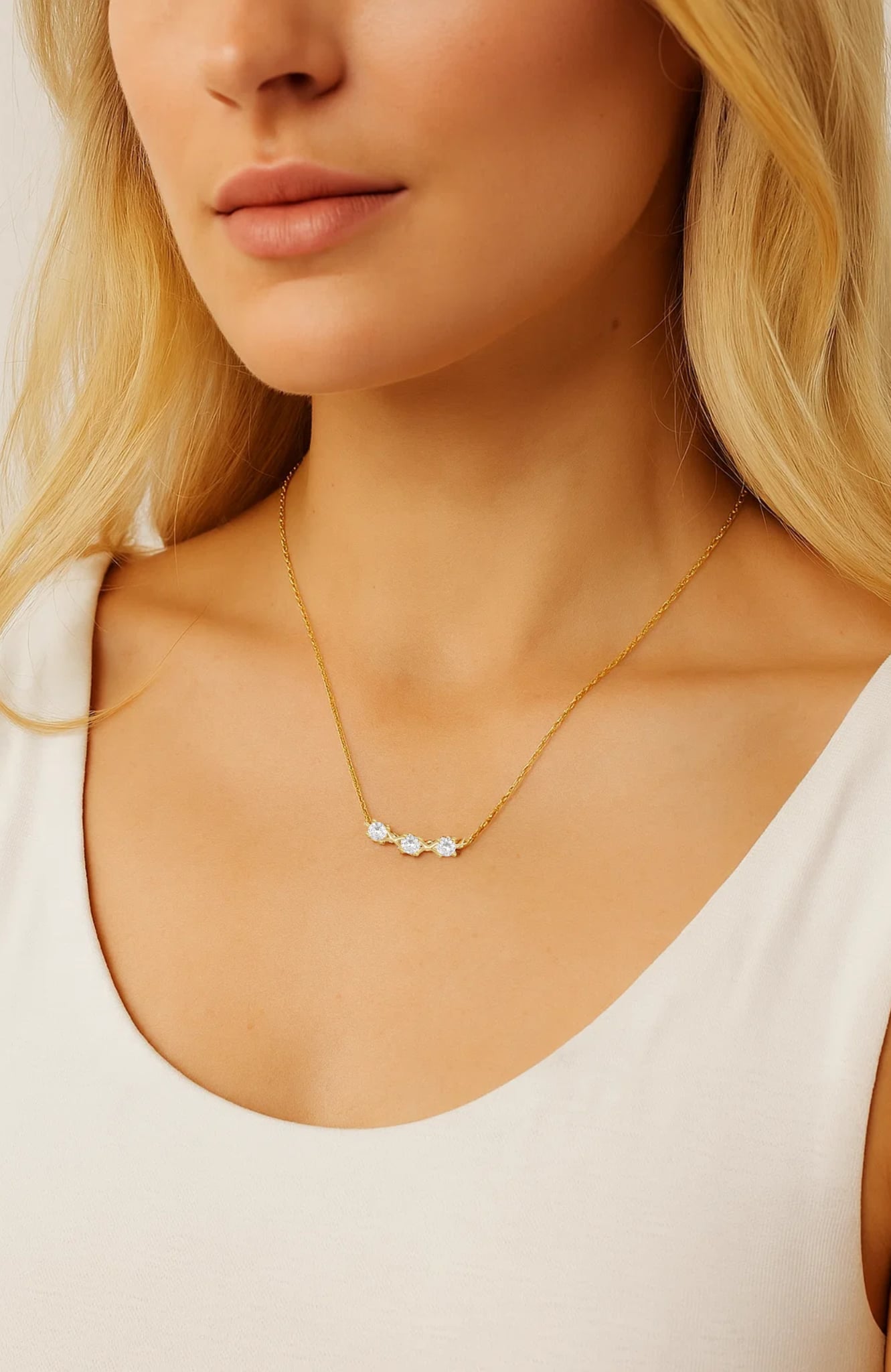 Delicate gold-tone necklace with three small round CZ stones on model
