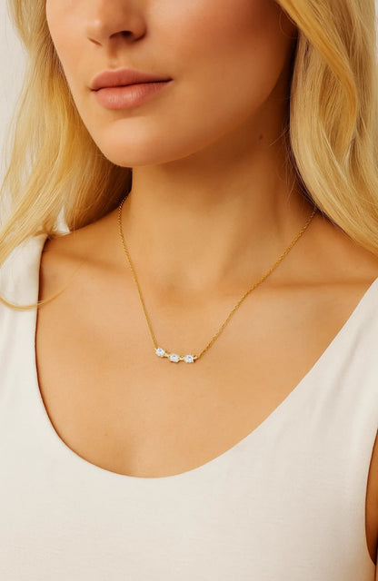 Delicate gold-tone necklace with three small round CZ stones on model