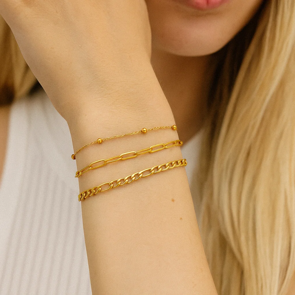 Gold-tone bracelet trio stacked on arm with smooth and bead-link chains