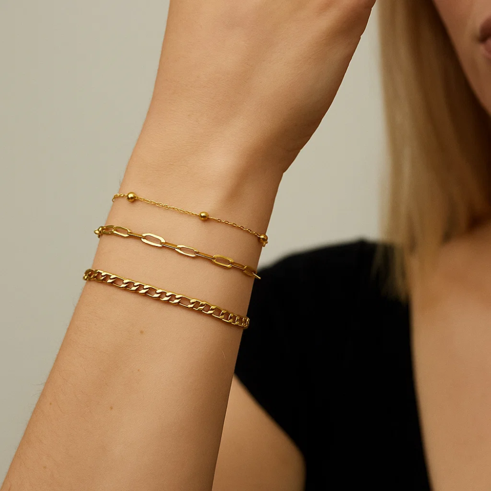 Three gold-tone bracelets stacked on forearm with clasp ends visible