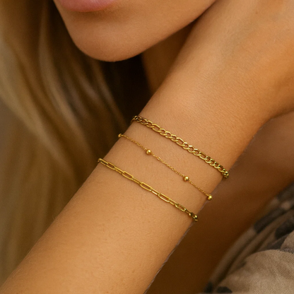 Stacked gold-tone bracelets with bead details and mixed chain links