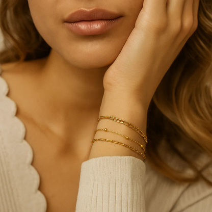 Stacked gold-tone bracelets on wrist with small bead accents