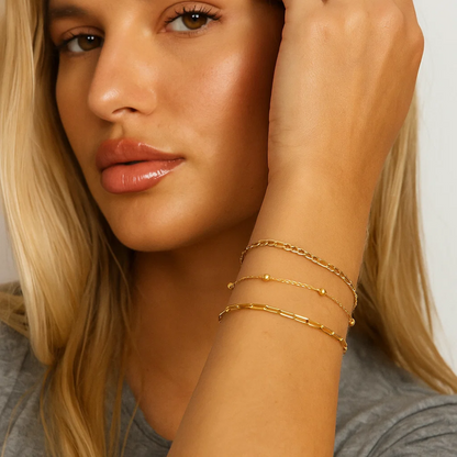 Gold-tone beaded bracelet trio with Figaro and paperclip links, stacked on wrist