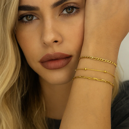 Stacked gold-tone chain and beaded bracelets with Figaro and paperclip links on wrist