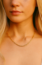Gold paperclip-link necklace worn by model at the neckline