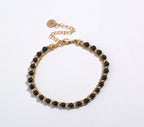 Gold-tone beaded friendship bracelet with black beads and round engraved charm clasp