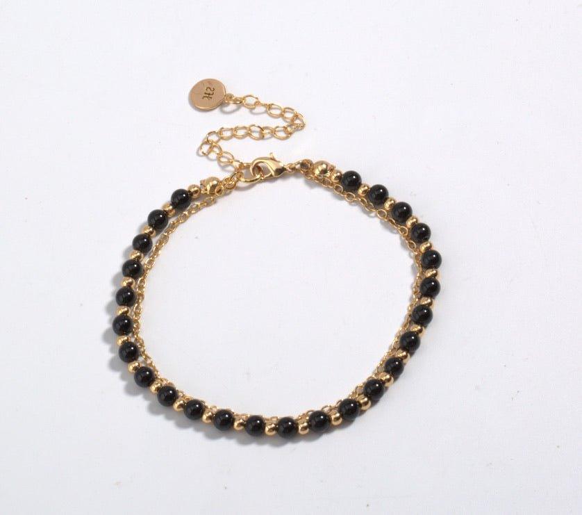 Gold-tone beaded friendship bracelet with black beads and round engraved charm clasp