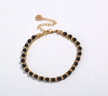 Gold-tone beaded friendship bracelet with black beads and round engraved charm clasp