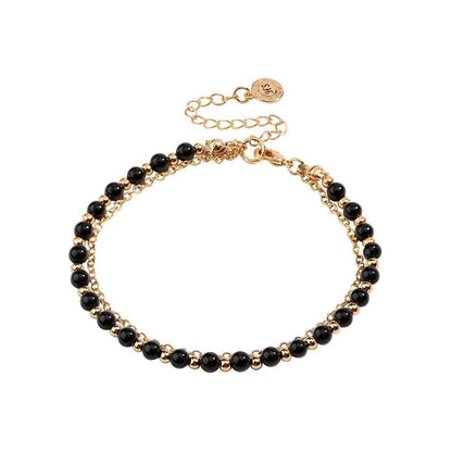 Gold beaded friendship bracelet with black beads and round charm centerpiece
