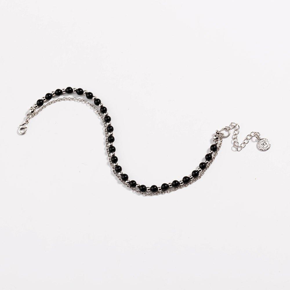 Silver beaded friendship bracelet with black beads and small round charm at end