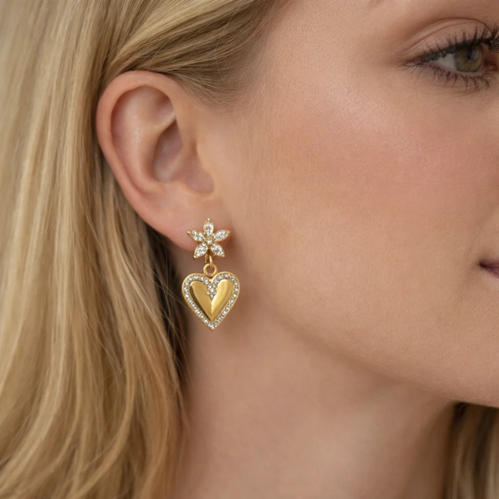 Gold-tone heart drop earrings with crystal flower top and heart dangle on ear