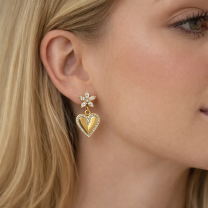 Gold-tone heart drop earrings with crystal flower top and heart dangle on ear