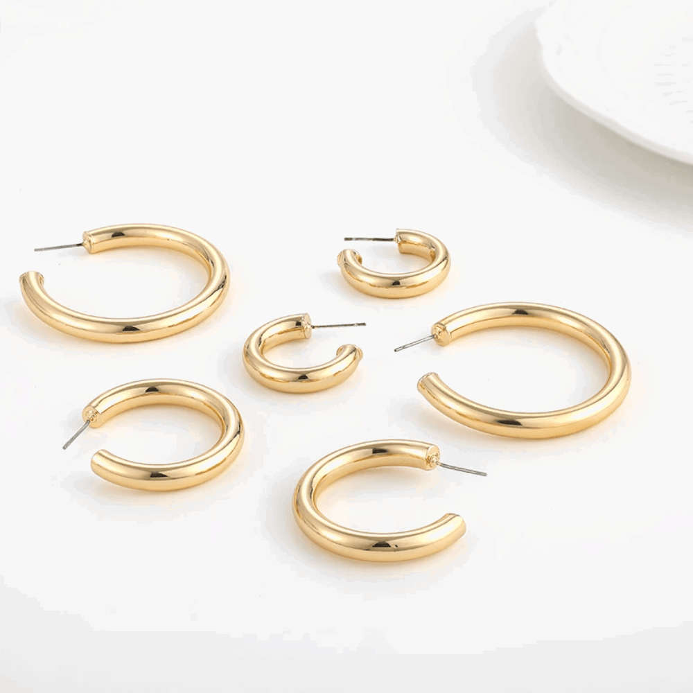Gold-tone hoop earrings assortment with pin clasp, various round sizes, flat lay.