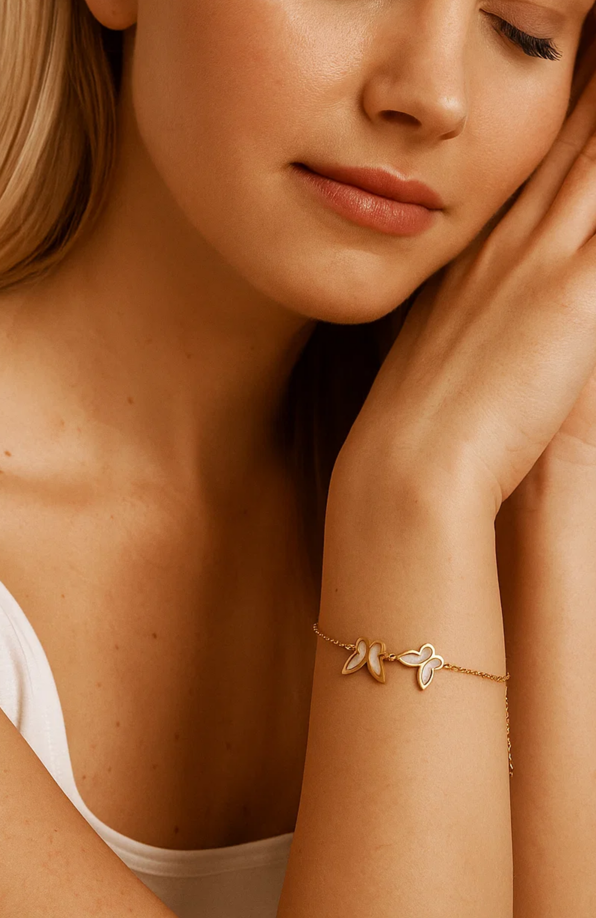 Gold bracelet on forearm with three butterfly charms and white shell inlay