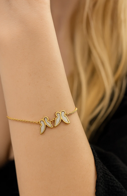 Gold butterfly bracelet with three charms and white shell inlay on wrist