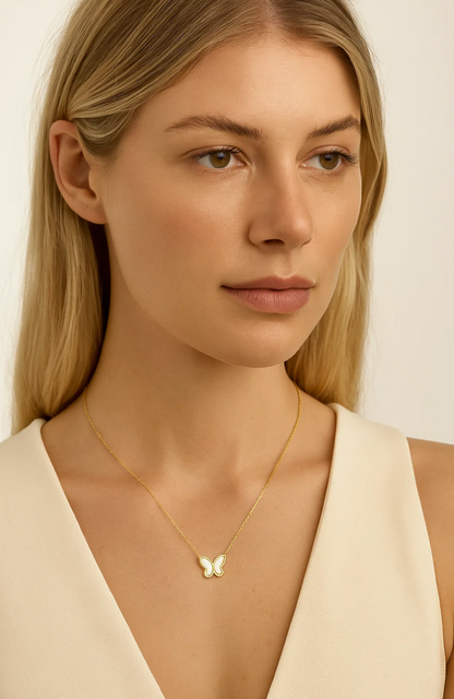 Gold-tone butterfly pendant necklace worn on a model with butterfly charm at center