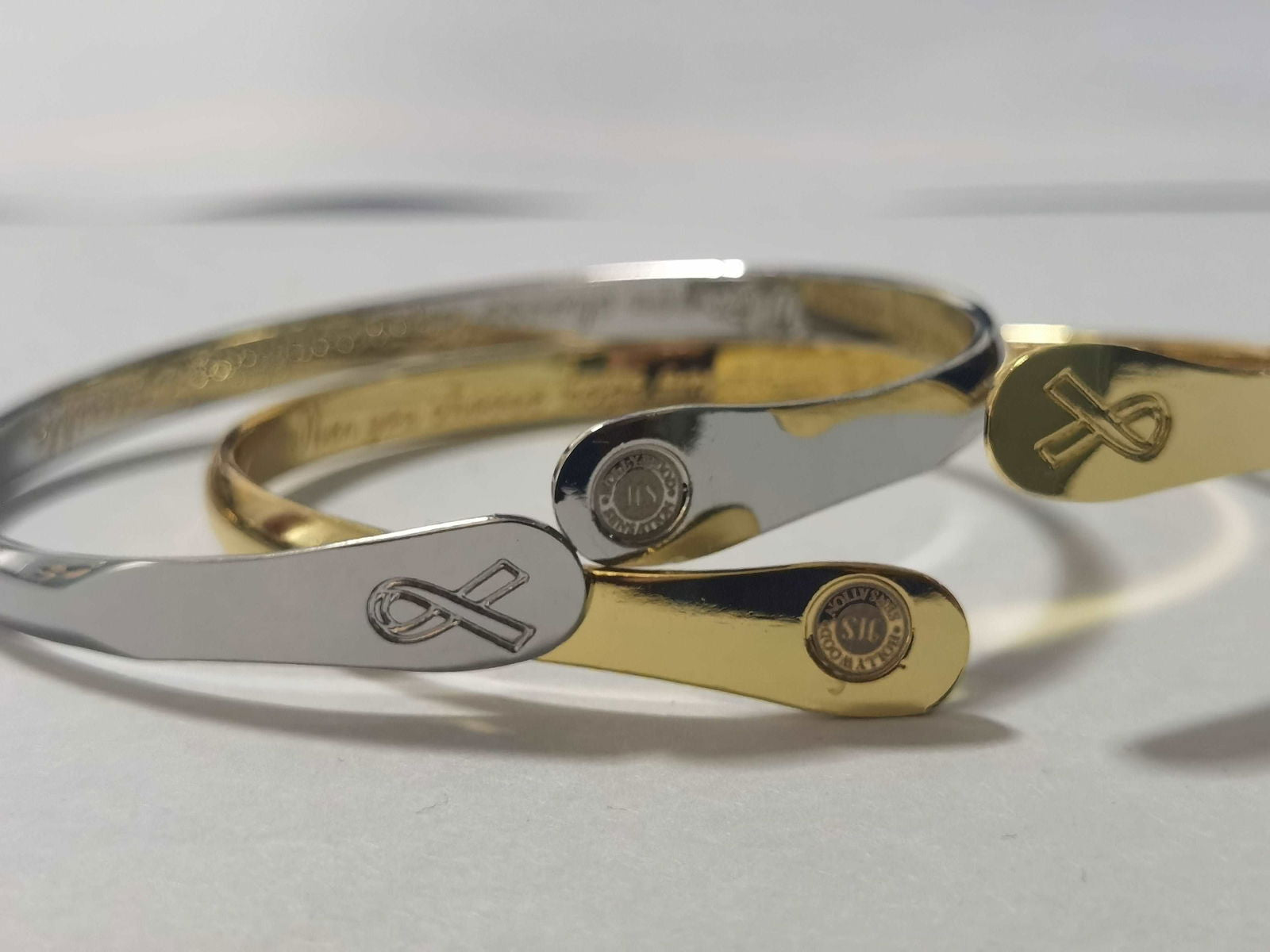 Pair of engraved bracelets, silver and gold cuffs with heart-and-arrow charm