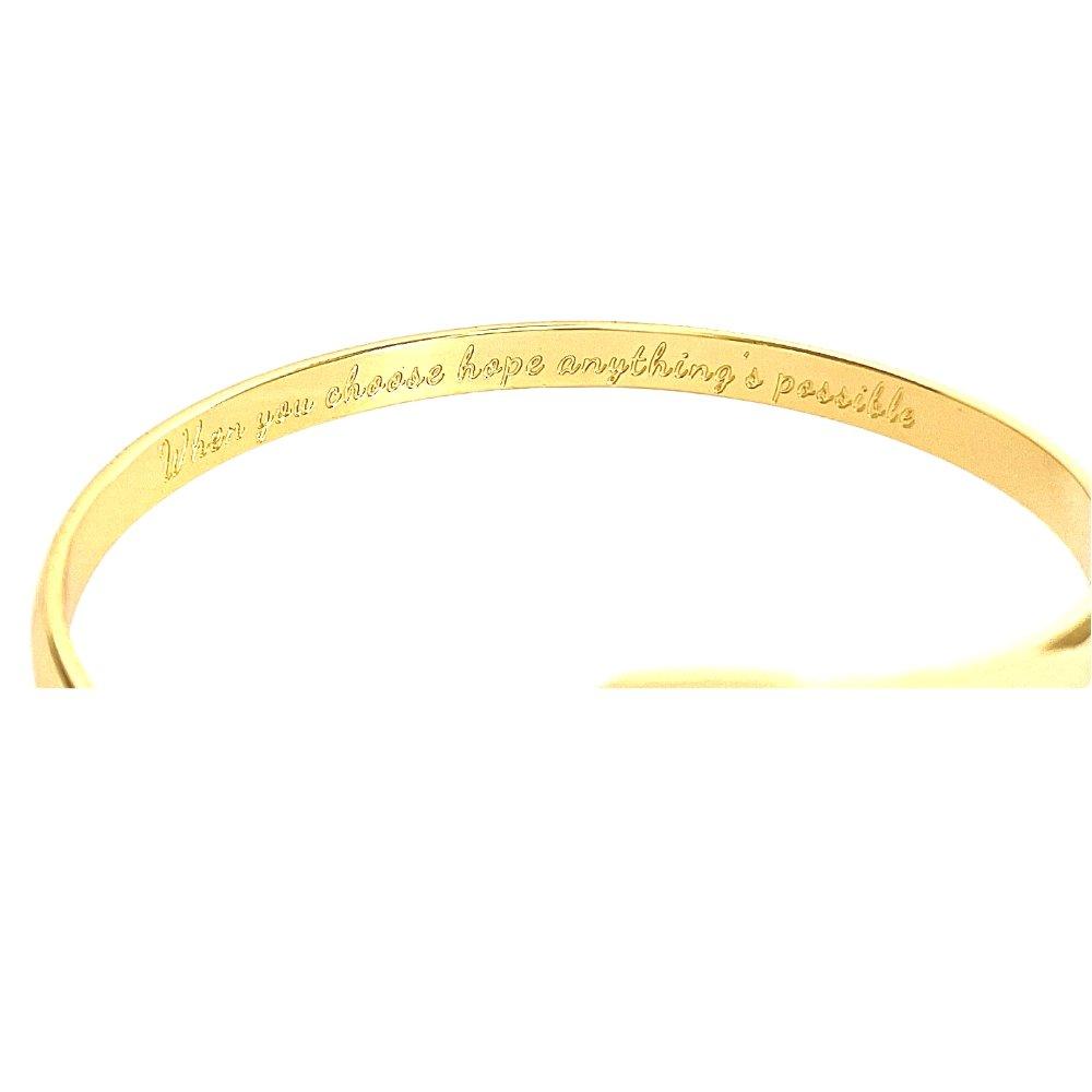 Gold engraved bracelet cuff showing inner message, ribbon emblem at center