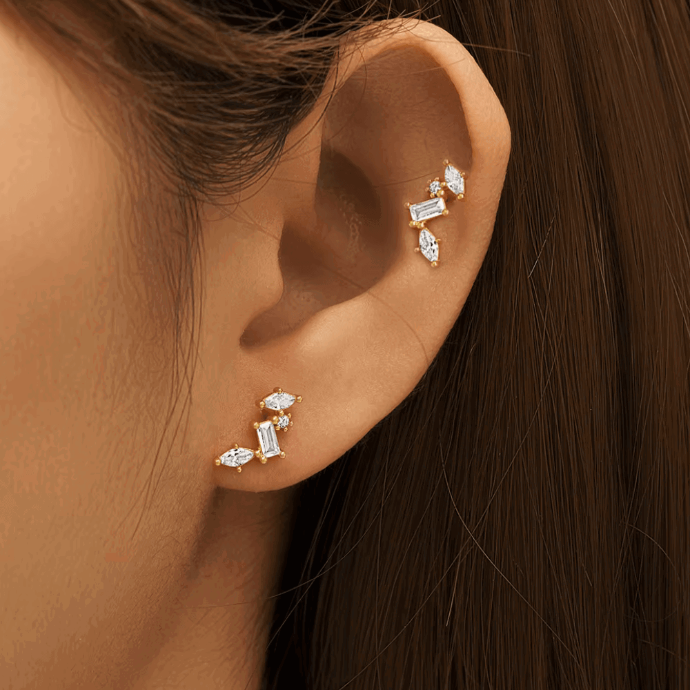 Gold-tone celestial cluster CZ earrings on ear with baguette and round stone accents