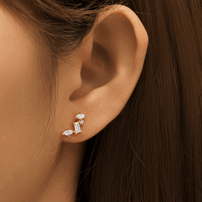 Gold-tone celestial cluster CZ earrings on ear, featuring oval and baguette stones