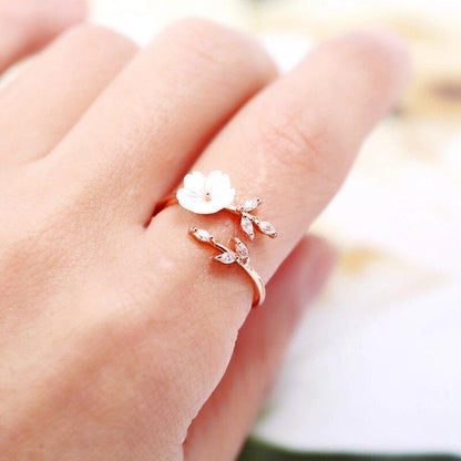 Close-up adjustable floral ring with white blossom centerpiece on rose-gold tone setting