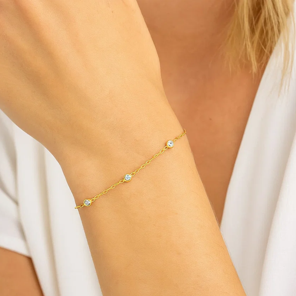 Gold cubic zirconia bezel link bracelet on wrist with round stones