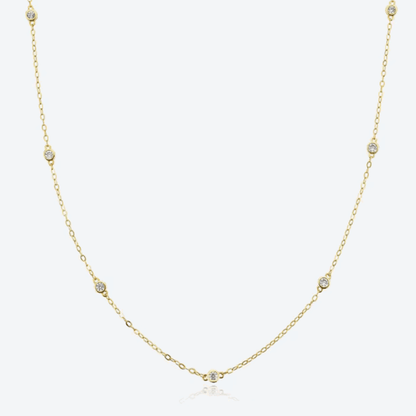 Gold-tone dainty necklace with round cubic zirconia halo bezel accents along chain