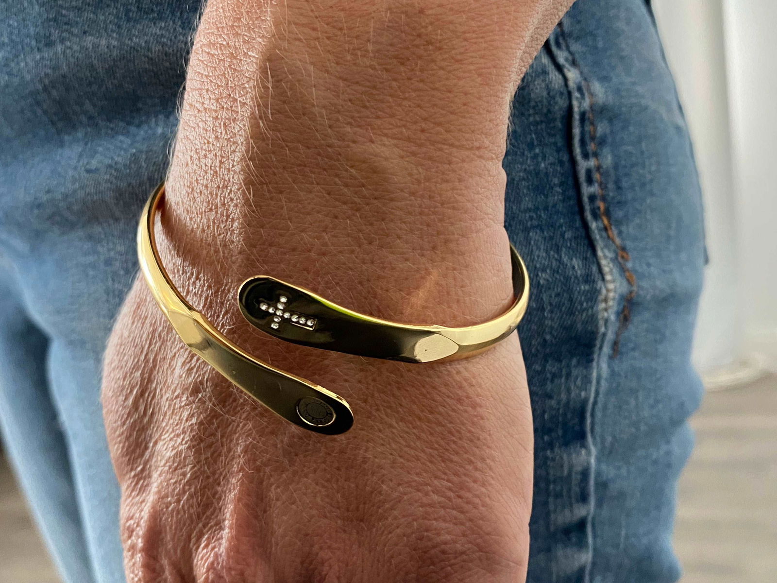 Gold bracelet on wrist with dark oval inlay and engraved markings
