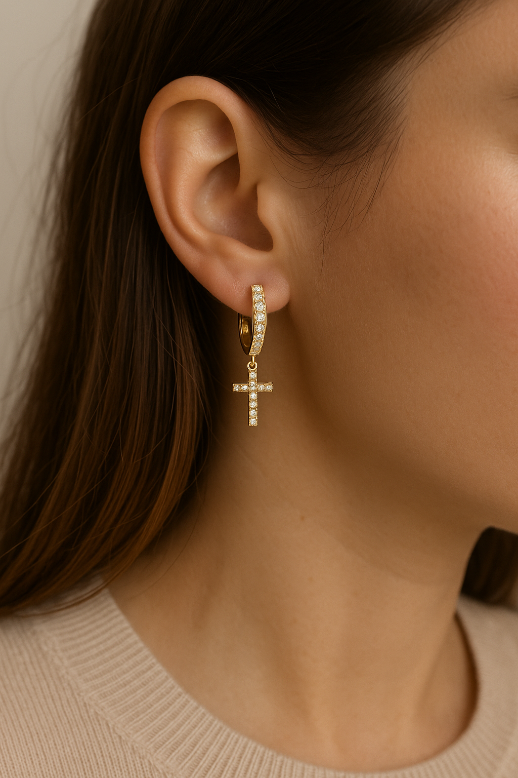 Gold cross dangle cubic zirconia earrings on ear with small hoop