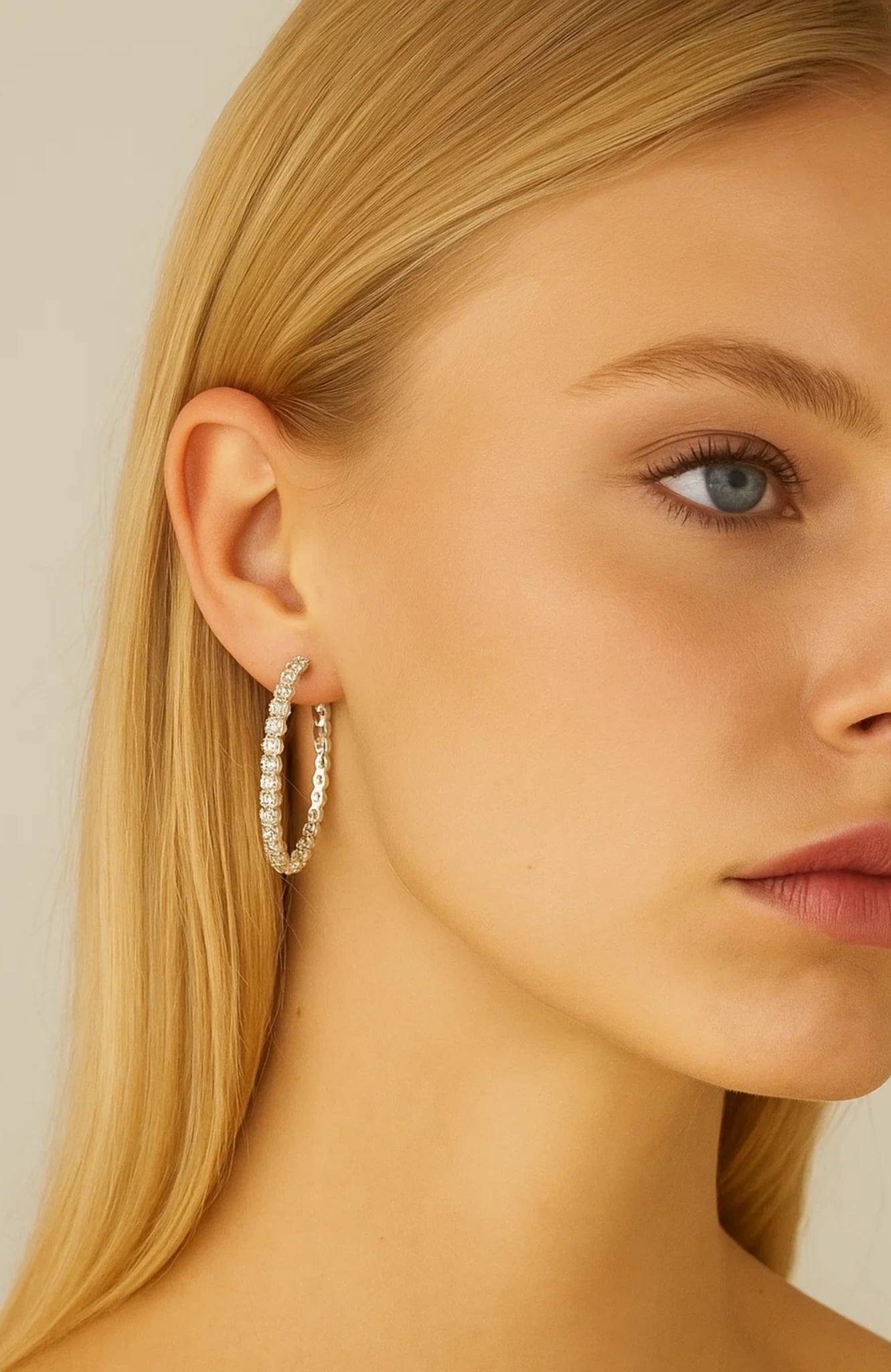 Gold-tone crystal hoop earring on model's ear